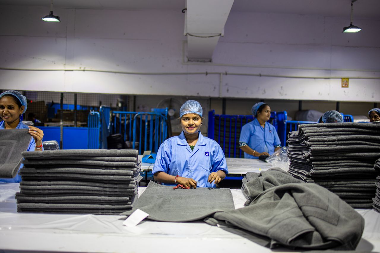 Smiling workers in a textile factory sorting large fabric stacks efficiently.